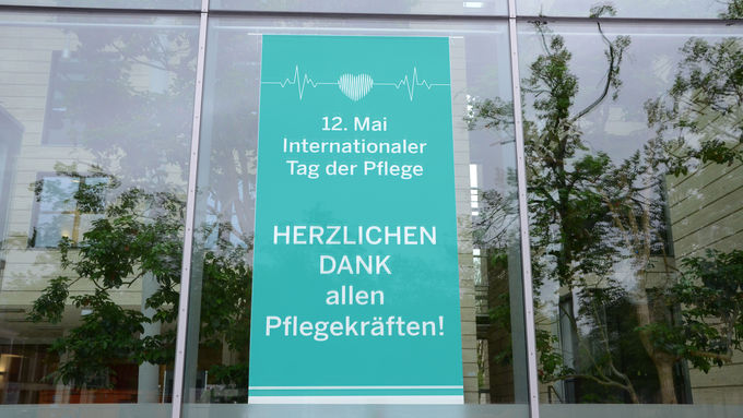 Ein Banner „Herzlichen Dank allen Pflegekräften“ zum Internationalen Tag der Pflege schmückt derzeit die Glasfassade am Dienstgebäude der Bezirksregierung Münster am Domplatz.